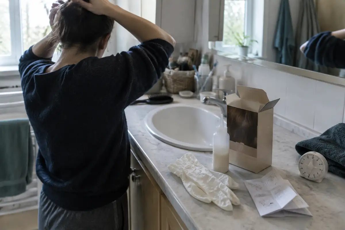 Gants, notice pliée et minuteur posés sur un plan de salle de bain
