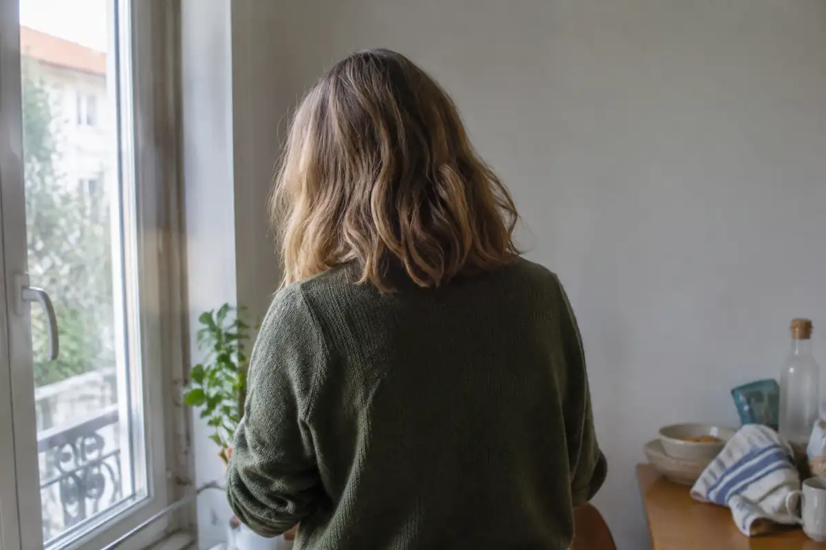 Cheveux blond foncé vus de dos dans la lumière d'une fenêtre