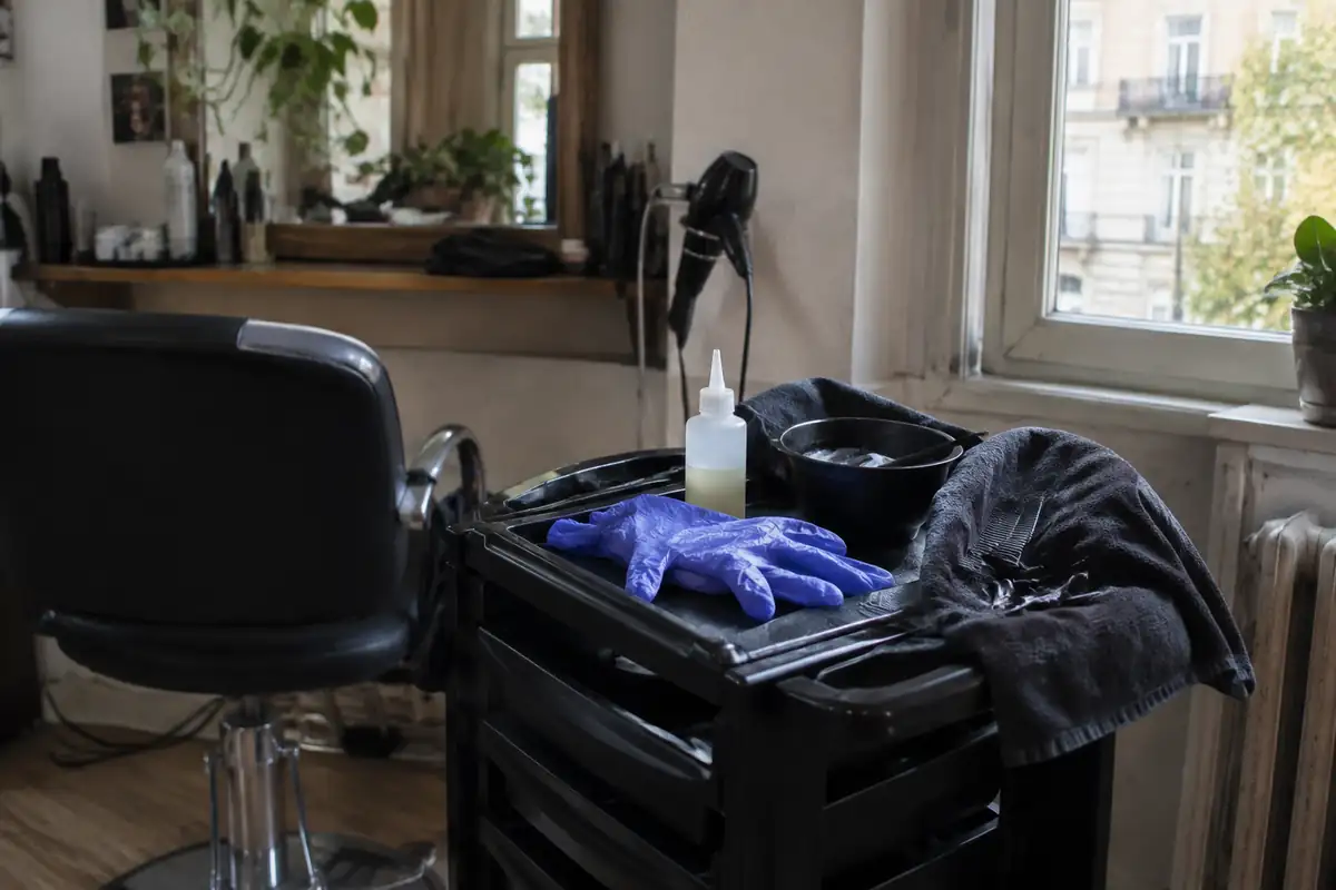 Petit flacon sans étiquette lisible et gants jetables sur un poste de coiffure